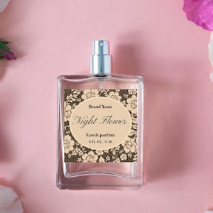 May include: A clear glass perfume bottle with a silver atomizer. The label reads "Night Flower" with floral and lace design. The background is a soft pink with white and purple flowers.
