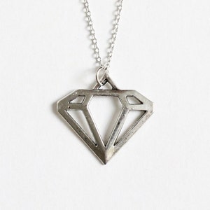 May include: A silver necklace with a geometric diamond pendant.