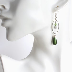 Puede incluir: Pendientes de plata con una cuenta verde en forma de l&aacute;grima y un aro de plata con una cuenta verde y blanca.