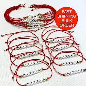 May include: Red string bracelets with white letter beads spelling "NATEYA" and "NATE". Gold accent beads are also present. The bracelets are displayed in a group, with a red circle that says "FAST SHIPPING BULK ORDER".