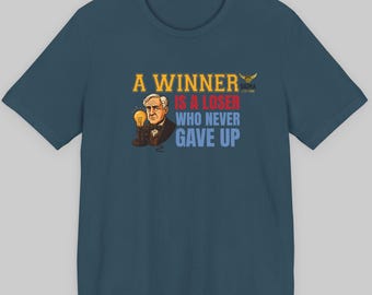 Puede incluir: Camiseta de color turquesa con la cita "A Winner Is A Loser Who Never Gave Up" en amarillo y azul. El diseño incluye una ilustración de un hombre sosteniendo una bombilla.