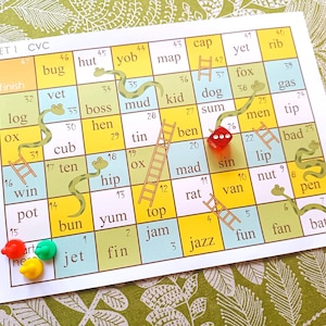 Könnte beinhalten: Ein farbenfrohes Spielbrett mit einem grünen Schlangen- und Leitern-Design. Das Brett zeigt Wörter wie "Bug", "Hütte", "Yob", "Karte", "Kappe", "noch", "Rippe", "Fuchs", "Gas", "Schlamm", "Kind", "Hund", "Summe", "Männer", "Tipp", "schlecht", "Lippe", "Nuss", "Stift", "Fledermaus", "Spaß", "Fan", "Jazz", "Marmelade", "Oben", "lecker", "Brötchen", "Topf", "Gewinn", "zehn", "Junges", "Henne", "Chef", "Protokoll", "Tierarzt" und "Fertig". Es befinden sich rote und grüne Spielfiguren auf dem Brett.