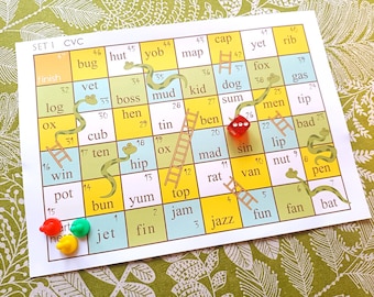 Könnte beinhalten: Ein farbenfrohes Spielbrett mit einem grünen Schlangen- und Leitern-Design. Das Brett zeigt Wörter wie "Bug", "Hütte", "Yob", "Karte", "Kappe", "noch", "Rippe", "Fuchs", "Gas", "Schlamm", "Kind", "Hund", "Summe", "Männer", "Tipp", "schlecht", "Lippe", "Nuss", "Stift", "Fledermaus", "Spaß", "Fan", "Jazz", "Marmelade", "Oben", "lecker", "Brötchen", "Topf", "Gewinn", "zehn", "Junges", "Henne", "Chef", "Protokoll", "Tierarzt" und "Fertig". Es befinden sich rote und grüne Spielfiguren auf dem Brett.