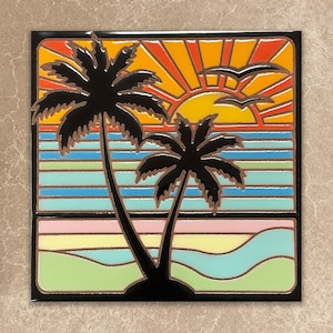 May include: A decorative tile featuring a tropical sunset scene. Two black palm trees are silhouetted against a vibrant sky with a yellow sun and orange rays. The ocean is depicted with blue and turquoise stripes, and two birds are flying.