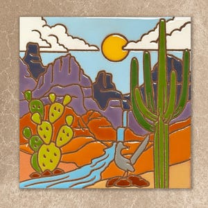 May include: Square ceramic tile featuring a desert landscape scene. The artwork depicts a bright yellow sun, blue sky, white clouds, and a green cactus. A roadrunner bird stands near a blue river. The background shows mountains in shades of purple and orange.