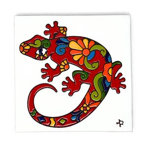 May include: A red, green, blue, yellow, and orange ceramic tile with a stylized image of a lizard with floral patterns.