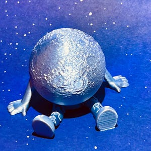 May include: A whimsical, light blue moon figure with arms and legs, set against a starry blue background. The moon has a textured surface, and the figure is in a seated position, evoking a playful, celestial theme.