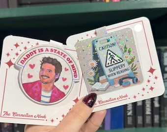 May include: A set of two decorative cards. One card features a portrait with the text "DADDY IS A STATE OF MIND". The other card has a caution sign with the text "SLIPPERY WHEN READING". Both cards have a holographic effect.