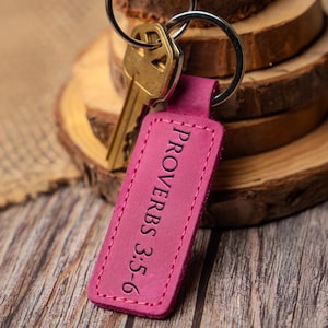 May include: A pink leather keychain with the text "Proverbs 3:5-6" embossed on it.
