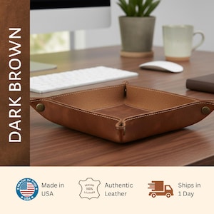 a brown leather desk organizer on a wooden desk, with a computer monitor, keyboard, mouse, and potted plant in the background.