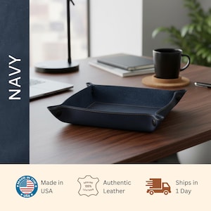 a navy blue leather tray on a wooden desk, with a laptop, notebook, and coffee cup nearby.