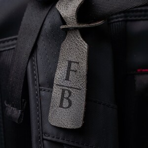 A close-up view of a black bag with a personalized monogrammed tag attached to it.