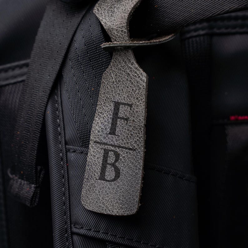 A close-up view of a black bag with a personalized monogrammed tag attached to it.