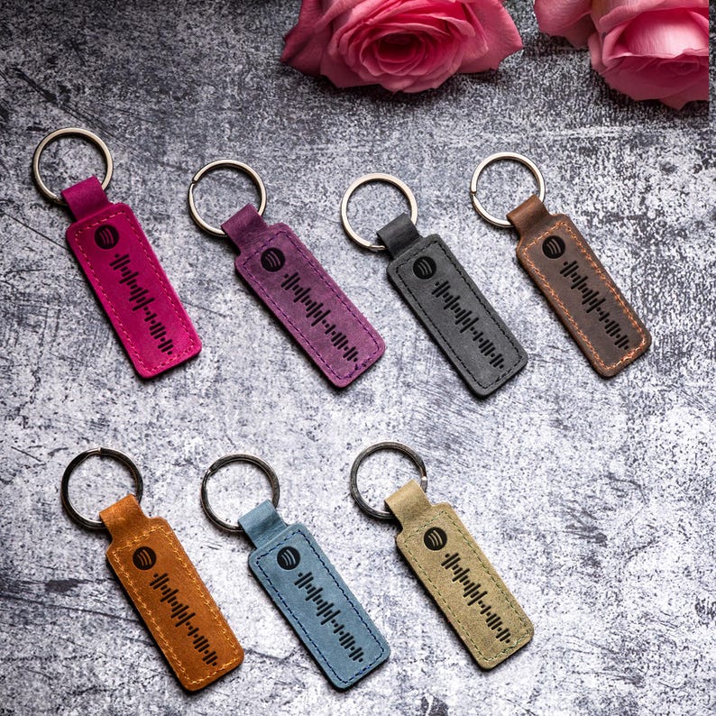 May include: Seven leather keychains with a black and white barcode design. The keychains are in various colors, including pink, purple, blue, brown, and tan.
