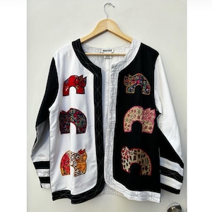 May include: A white and black jacket with a contrasting colour design. The jacket has a mandarin collar and a front zip closure. The jacket is decorated with colourful embroidered animal figures. The label on the jacket reads "marisol".