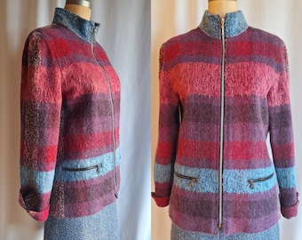 Op de afbeelding: Een gestreept, veelkleurig jack met een ritssluiting. Het jack is gemaakt van een pluche, textuurrijke stof en heeft twee zakken aan de voorkant. Het jack wordt gepresenteerd op een mannequin.