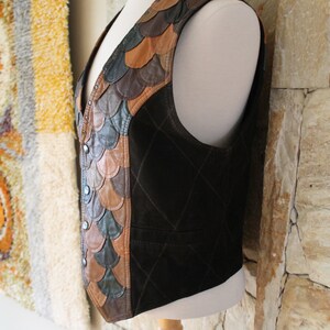 May include: A brown leather waistcoat with a quilted design and a decorative panel of brown, tan, and green leather scales on the left side.