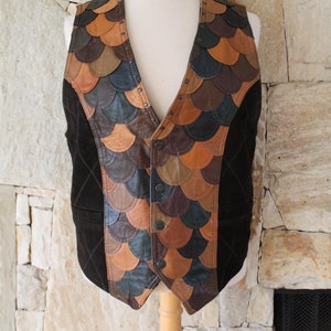 May include: A brown leather waistcoat with a unique design featuring a patchwork of different coloured leather pieces. The waistcoat has a V-neck and a button closure.