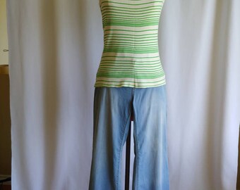 May include: A white tank top with green horizontal stripes. The tank top is on a mannequin wearing blue denim jeans.