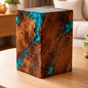 Peut inclure: Bloc de bois artisanal avec un grain brun foncé. Des incrustations de résine turquoise vif créent un contraste saisissant. Cette pièce cubique est un élément décoratif, idéal pour une maison moderne.