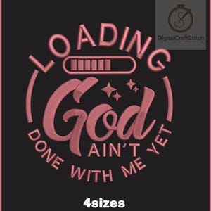 Puede incluir: Un diseño de bordado con el texto LOADING en un arco circular sobre una barra de progreso, la palabra God en letra cursiva grande debajo, y el texto AIN'T DONE WITH ME YET en un arco circular en la parte inferior, todo en rosa sobre fondo negro.