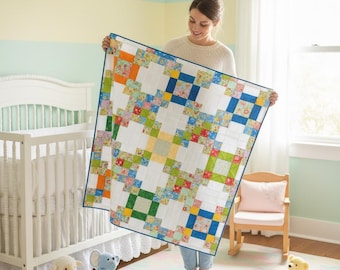 May include: A square patchwork quilt featuring a grid of white fabric squares interspersed with smaller squares in various floral and solid colors including blue, green, orange, and yellow, finished with a thin dark blue border around the edges.