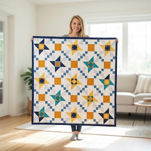 Peut inclure: Une courtepointe faite à la main avec un motif d'étoiles dans des tons de bleu, jaune et orange sur fond blanc. La courtepointe a une bordure bleu foncé. La courtepointe mesure environ 152 cm sur 152 cm.