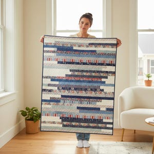 以下が含まれることがあります： パッチワークデザインの手作りキルト。キルトは、青、白、赤のさまざまな色合いの水平ストライプが特徴で、花柄と幾何学模様があります。キルトは窓の前に掲げられています。