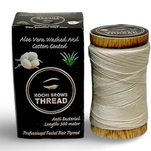 May include: A spool of off-white facial hair thread next to a black rectangular box labeled Kochi Brows Thread. The packaging features text stating Aloe Vera Washed And Cotton Coated, Anti Bacterial, and Length 300 meter, with illustrations of a cotton boll and an aloe plant.