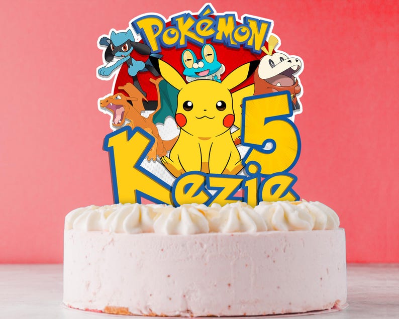 May include: A round pink cake topped with white frosting and a colorful Pok&eacute;mon-themed cake topper. The topper features Pikachu, other Pok&eacute;mon characters, the number 5, and the name "Kezie". The background is a solid red.