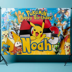 May include: A colorful birthday banner featuring the Pok&eacute;mon characters Pikachu, Charizard, and Eevee. The banner has the text "Pok&eacute;mon Happy Birthday!" and the name "Noah" with the number "3". The background is a blue sky with clouds.