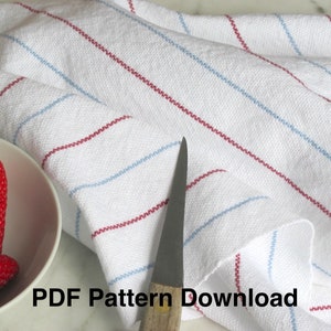 A Hand Woven white kitchen towel with red and blue stripes, shown as an example for Kitchen Tea Towels Weaving Pattern Draft PDF, Easy Beginner Handweaving 4H Harness Shaft Table or Floor Loom Digital Download Instructions as an artful Kitchenware Cookware Accessory for Gourmet Chef Home Baking, Cooking Designed by Master Weaver Amy C. Lund. The towel is folded and lying on a marble surface. A knife and a bowl of strawberries in the image. The text 'PDF Pattern Download' is visible in the image.