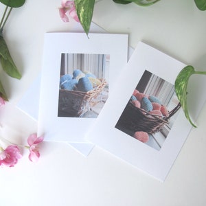 Two Spring Easter Egg Basket Greeting Cards, Blank Inside, Printable Instant Download PDF, Weaving Textile Art for Inspiration Hope Celebration. The cards are on a white surface with a green plant and pink flowers.