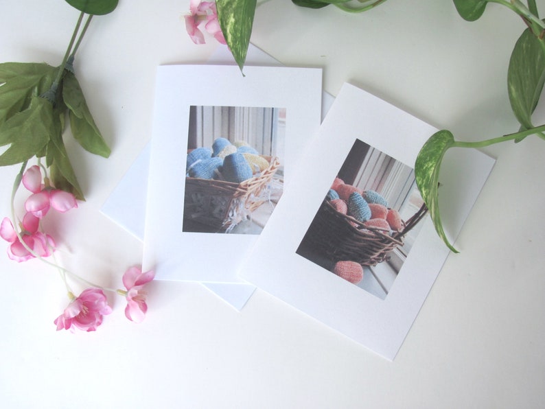 Two Spring Easter Egg Basket Greeting Cards, Blank Inside, Printable Instant Download PDF, Weaving Textile Art for Inspiration Hope Celebration. The cards are on a white surface with a green plant and pink flowers.