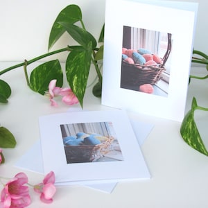 Two Spring Easter Egg Basket Greeting Cards, Blank Inside, Printable Instant Download PDF, Weaving Textile Art for Inspiration Hope Celebration. The cards are on a white surface with a green plant and pink flowers.