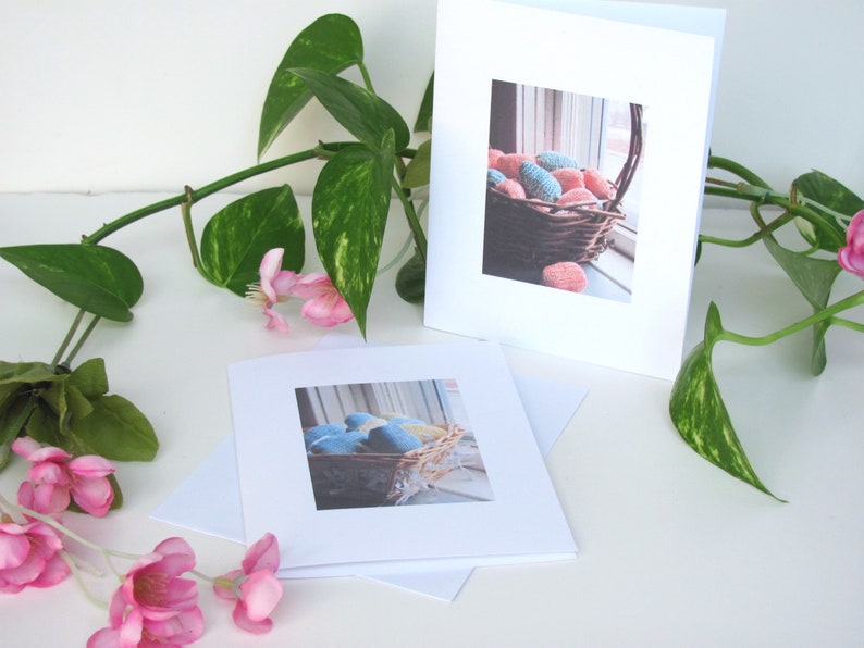 Two Spring Easter Egg Basket Greeting Cards, Blank Inside, Printable Instant Download PDF, Weaving Textile Art for Inspiration Hope Celebration. The cards are on a white surface with a green plant and pink flowers.