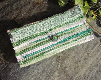 May include: A green and white woven clutch with a green button. The clutch is made of recycled materials and has a unique, handmade look.