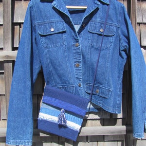 Small Crossbody Bag Wallet or Phone Purse is Handmade, Artisan Hand Woven in Indigo Navy Blue with Zero Waste, Eco Friendly Upcycled Cloth, Vegan Recycled Fabric. This Sustainable Slow Fashion Accessory Handbag, Boho Cash Change Pouch or Money Shoulder Pouch is Handcrafted by Amy C. Lund. Styled with a blue denim jacket.