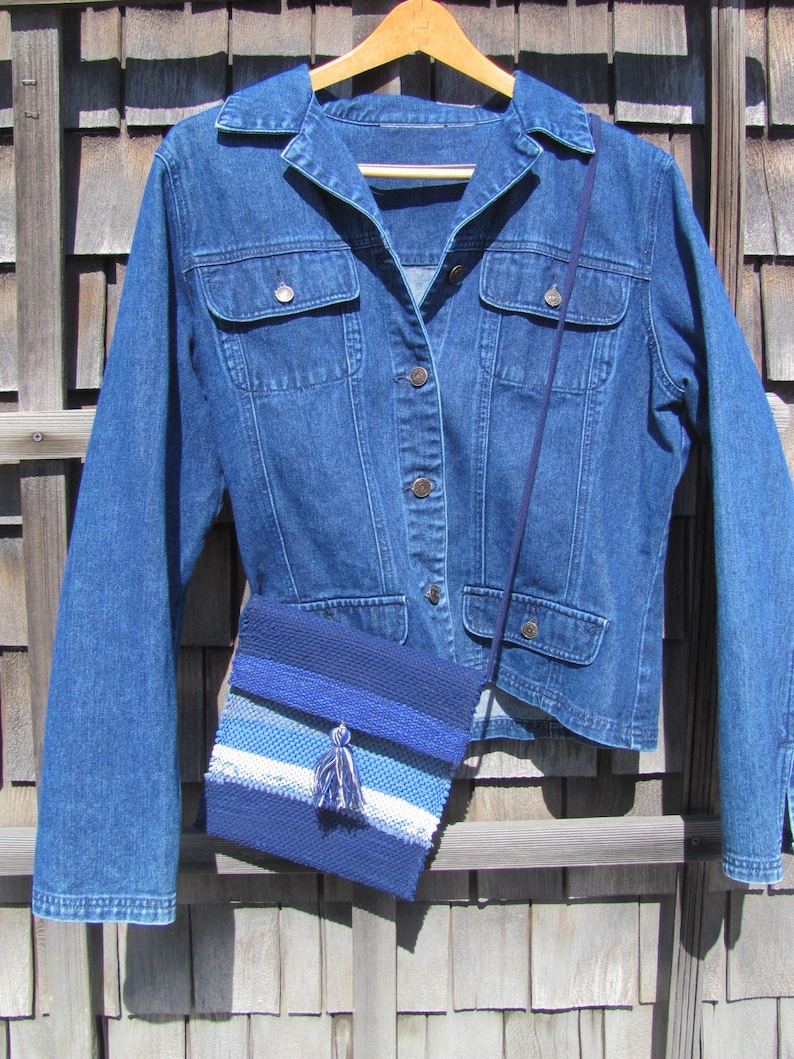 Small Crossbody Bag Wallet or Phone Purse is Handmade, Artisan Hand Woven in Indigo Navy Blue with Zero Waste, Eco Friendly Upcycled Cloth, Vegan Recycled Fabric. This Sustainable Slow Fashion Accessory Handbag, Boho Cash Change Pouch or Money Shoulder Pouch is Handcrafted by Amy C. Lund. Styled with a blue denim jacket.