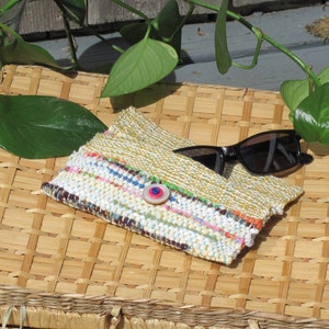 Boho Wallet Smart Phone Case, Small Hand Woven Clutch Purse, Cloth Fabric Soft Eyeglass Case Handmade Vegan Eco Friendly Zero Waste Upcycled Recycled Bag, Sustainable Slow Fashion Accessory with Sunny Yellow Accents Handcrafted by Amy C. Lund! Showing button closure. Styled open with sunglasses on a basket with green leaves.
