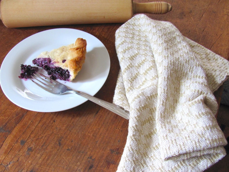 Handcrafted Butter Cream Artisan Hand Woven Cotton Kitchen Dish Towel, Gourmet Chef Gift or Home Cooking Baking Gift, Rustic Country French Cottage Modern Farmhouse Cookware or Kitchenware Decor Accessory.  Styled with a wooden rolling pin, slice of blueberry pie on a white plate with a fork.