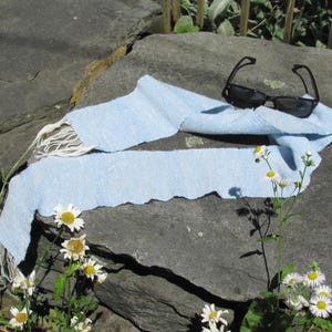 Artisan Handmade Light Blue Spring Summer Scarf, Minimalist Zen Serenity, Simplicity, Soothing Tranquil Tones Meditation Table Runner, Gender Neutral Unisex Men's or Women's Om Yoga, Spiritual Prayer Clothing, Hand Woven Cotton Scarf, Slow Fashion Accessory or Home Decor Accent Gift Idea. Styled casually on a gray rock with black sunglasses and white daisies.