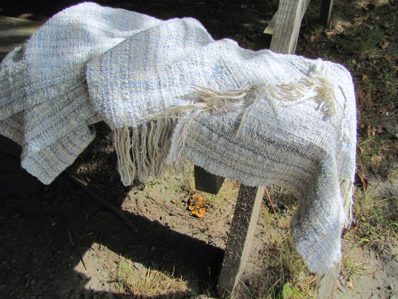 Handmade Light Blue Chalcedony Artisan Hand Woven Scarf Shawl or Table Runner for Positive Natural Energy, Spiritual Serenity, Harmony, Grounding Meditation Prayer is a Gender Neutral Unisex Men's Women's Long Fall, Winter, Spring, Urban Casual Rustic Fashion Accessory Wrap or Home Decor Accent Handcrafted by Amy C. Lund in Cotton Blend. Styled casually on a weathered wood table outdoors.