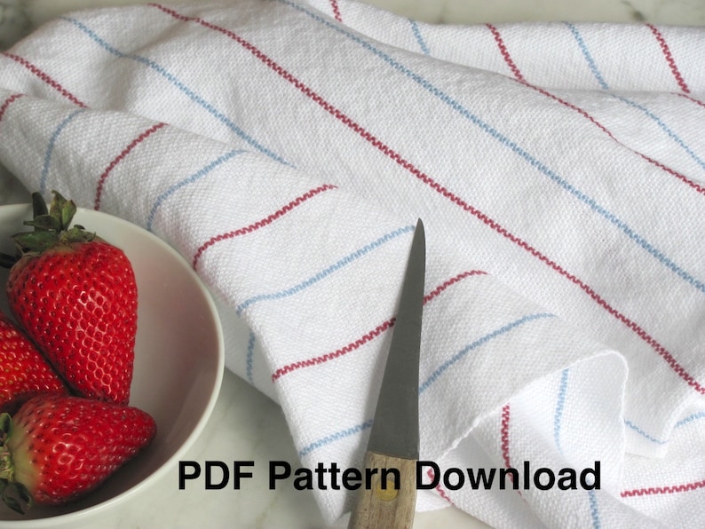 A Hand Woven white kitchen towel with red and blue stripes, shown as an example for Kitchen Tea Towels Weaving Pattern Draft PDF, Easy Beginner Handweaving 4H Harness Shaft Table or Floor Loom Digital Download Instructions as an artful Kitchenware Cookware Accessory for Gourmet Chef Home Baking, Cooking Designed by Master Weaver Amy C. Lund. The towel is folded and lying on a marble surface. A knife and a bowl of strawberries in the image. The text 'PDF Pattern Download' is visible in the image.