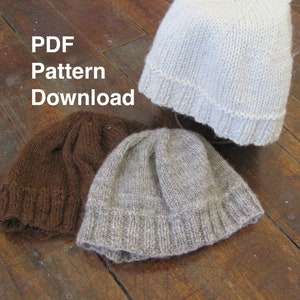 May include: Three knitted hats in different colours: brown, light grey, and white. The hats are on a wooden surface. The text "PDF Pattern Download" is visible in the image.