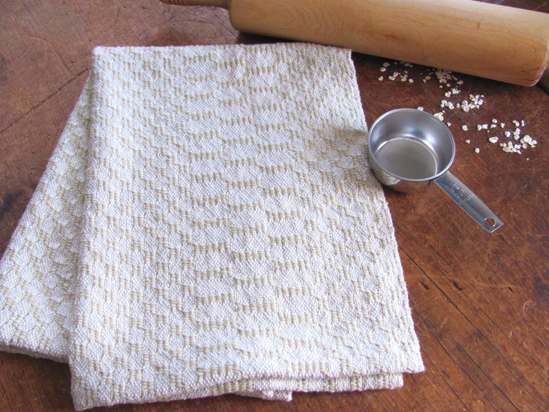 Handcrafted Butter Cream Artisan Hand Woven Cotton Kitchen Dish Towel, Gourmet Chef Gift or Home Cooking Baking Gift, Rustic Country French Cottage Modern Farmhouse Cookware or Kitchenware Decor Accessory.  Styled with a metal measuring cup. a wooden rolling pin, oats.