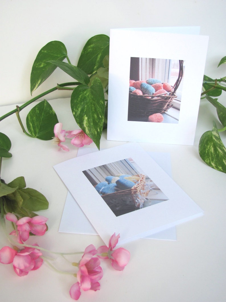 Two Spring Easter Egg Basket Greeting Cards, Blank Inside, Printable Instant Download PDF, Weaving Textile Art for Inspiration Hope Celebration. The cards are on a white surface with a green plant and pink flowers.