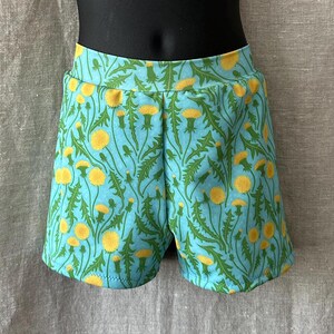 Puede incluir: Shorts azules con estampado de diente de león. Los shorts tienen una cintura elástica y un ajuste holgado.