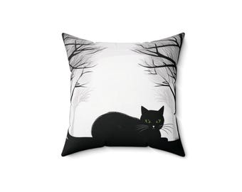 May include: Black and white throw pillow with a silhouette of a black cat with green eyes sitting in front of a pair of bare trees.