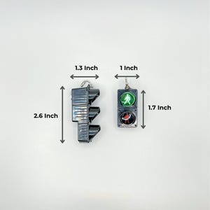 May include: Two traffic light keychains, one red, yellow, and green, and the other green and red. The red, yellow, and green traffic light keychain is 2.6 inches tall and 1.3 inches wide. The green and red traffic light keychain is 1.7 inches tall and 1 inch wide.